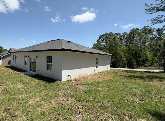 view of side of home with stucco siding and a yard