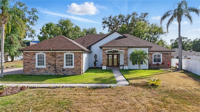 view of front of house featuring fence, french doors, a front yard, and stone siding