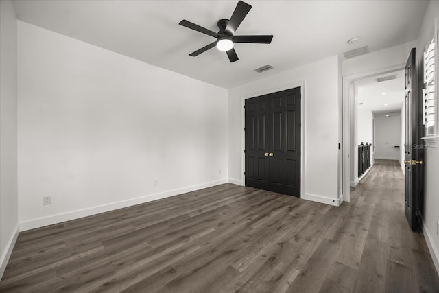 unfurnished bedroom featuring dark wood-style floors, baseboards, a closet, and a ceiling fan