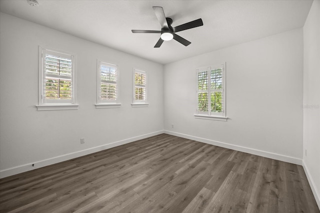 spare room featuring healthy amount of natural light, baseboards, dark wood finished floors, and ceiling fan