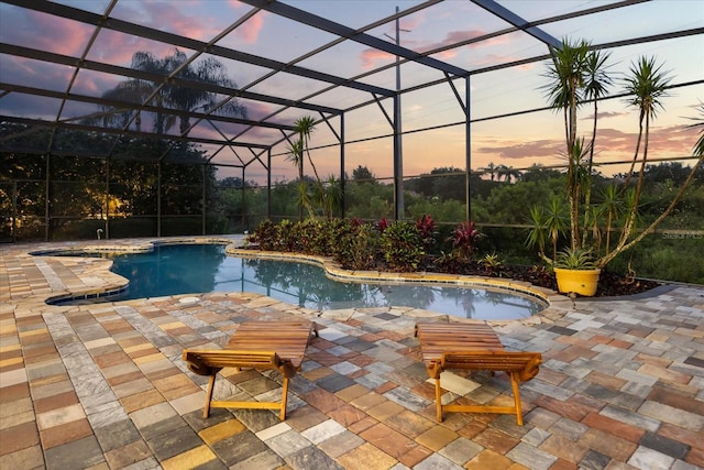 pool at dusk featuring a patio area, an outdoor pool, and a lanai