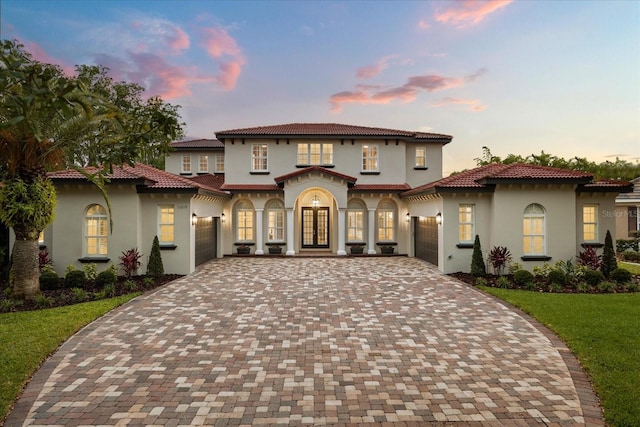 mediterranean / spanish-style home featuring a garage, decorative driveway, and stucco siding