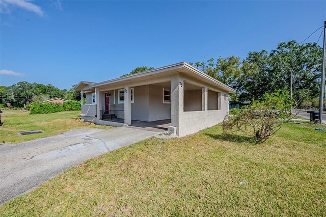 72 Campus View Dr, Orlando, FL 32810 - view of front facade featuring covered porch, stucco siding, a front yard, concrete driveway, and a carport