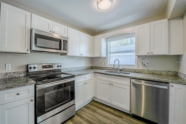 72 Campus View Dr, Orlando, FL 32810 - kitchen featuring white cabinetry, appliances with stainless steel finishes, a sink, and light wood-type flooring