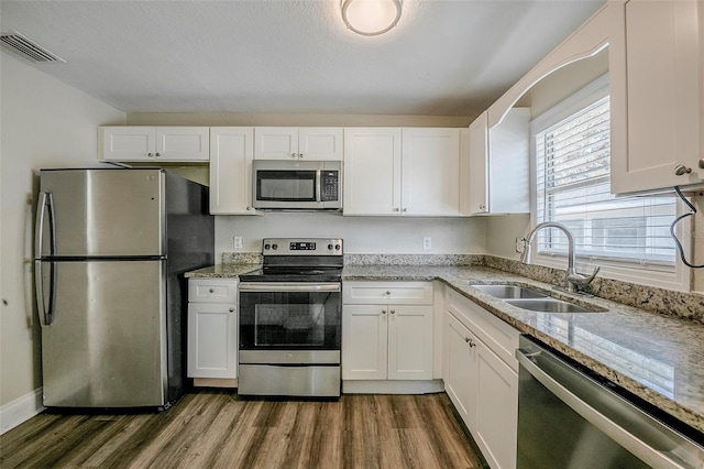72 Campus View Dr, Orlando, FL 32810 - kitchen with white cabinets, light stone countertops, a sink, stainless steel appliances, and dark wood-type flooring