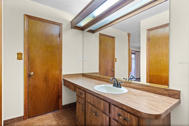 bathroom with a textured ceiling, tile patterned floors, and vanity