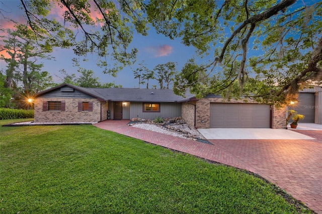ranch-style home featuring an attached garage, decorative driveway, a lawn, and brick siding