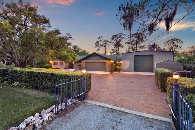 view of front of house featuring decorative driveway, fence, and a garage