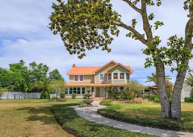 view of front of home with metal roof, a front lawn, a chimney, and fence