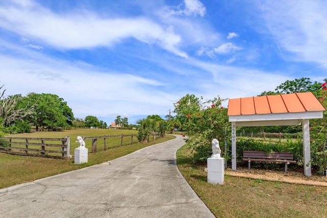 view of community featuring fence, a yard, and a rural view