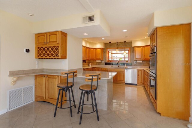 kitchen featuring a breakfast bar area, visible vents, a peninsula, and appliances with stainless steel finishes