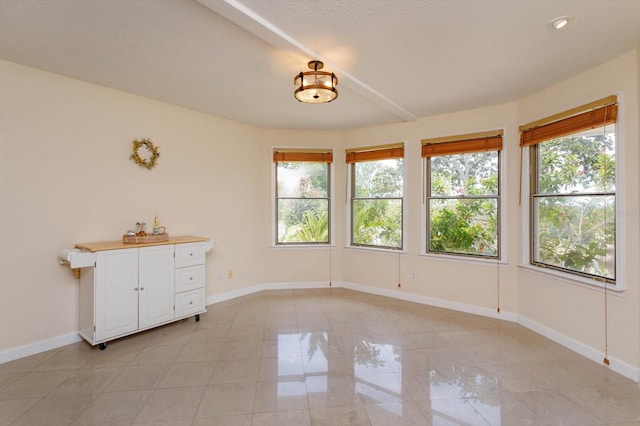 empty room featuring baseboards and light tile patterned floors