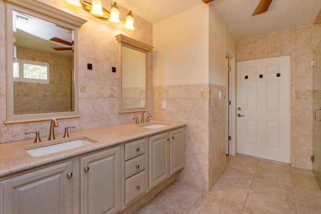 bathroom featuring tile walls, a sink, a shower stall, and tile patterned floors