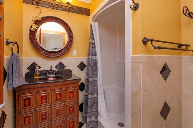 bathroom with a stall shower, tile walls, wainscoting, and vanity