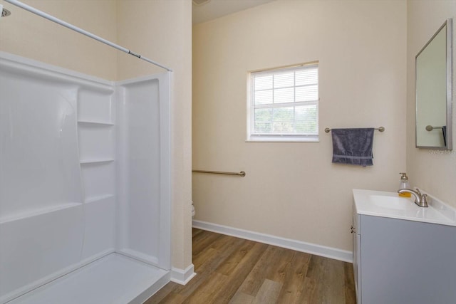 full bath featuring a stall shower, baseboards, toilet, wood finished floors, and vanity