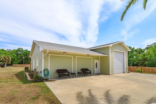 exterior space featuring a garage, fence, a lawn, and a patio area