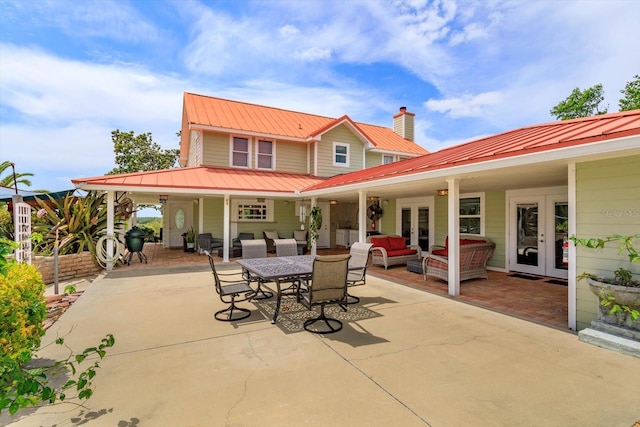 rear view of property featuring metal roof, a patio area, french doors, and an outdoor hangout area