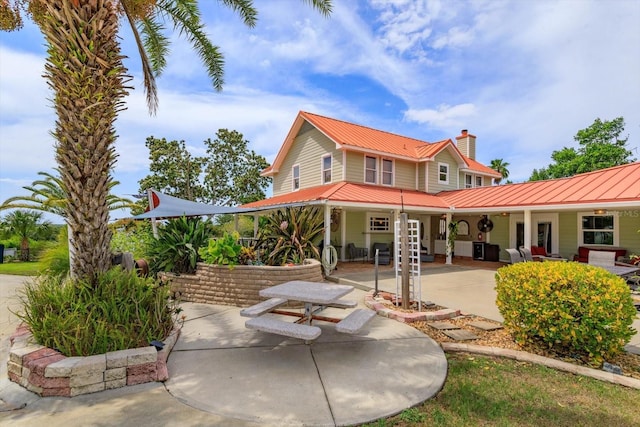 36408 E Eldorado Lake Dr, Eustis, FL 32736 - rear view of property featuring metal roof, a chimney, covered porch, and a standing seam roof