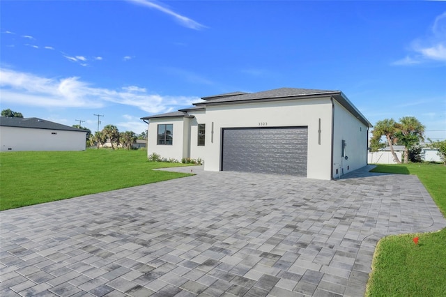 prairie-style home with decorative driveway, a front lawn, a garage, and stucco siding