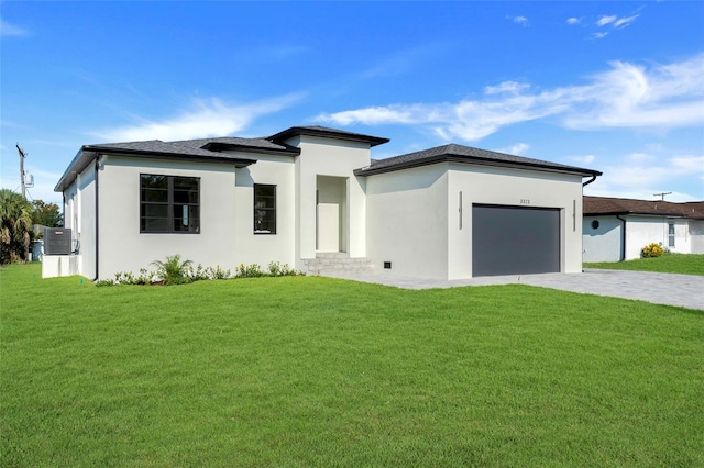 prairie-style house with a front yard, central air condition unit, decorative driveway, and an attached garage