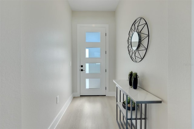 doorway featuring light wood finished floors and baseboards