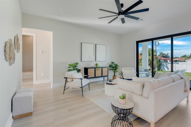 living room with baseboards, a ceiling fan, and light wood-style flooring