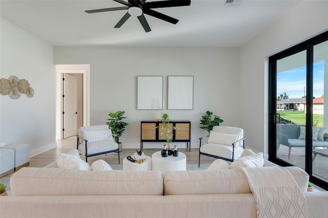 living room with a ceiling fan, visible vents, baseboards, and light wood-style floors
