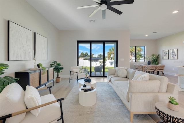 living room featuring light wood-style flooring, visible vents, ceiling fan, baseboards, and recessed lighting