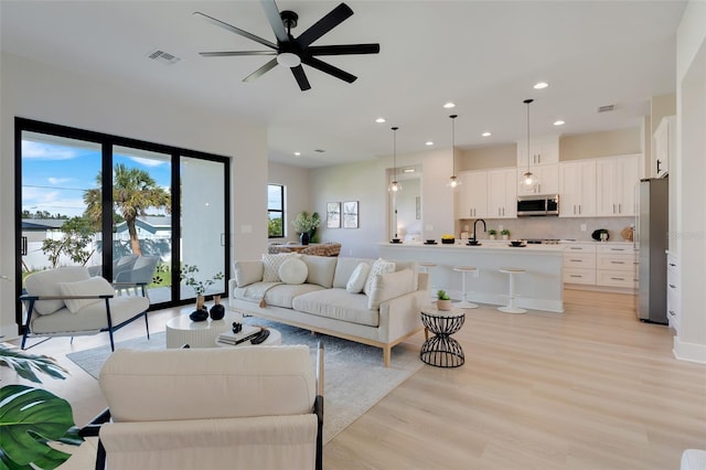 living area featuring recessed lighting, a ceiling fan, visible vents, and light wood-style flooring