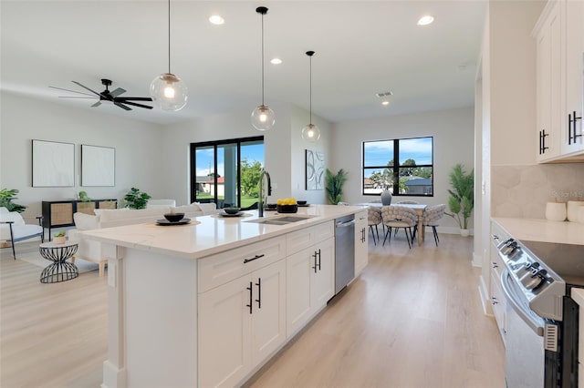 kitchen featuring a sink, appliances with stainless steel finishes, light wood-style floors, open floor plan, and recessed lighting