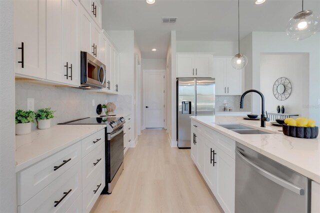kitchen with decorative backsplash, a sink, appliances with stainless steel finishes, visible vents, and decorative light fixtures