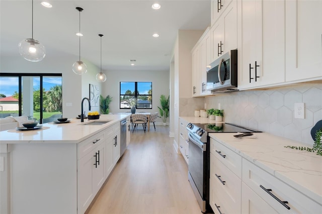 kitchen with white cabinets, light wood-style flooring, a sink, stainless steel appliances, and recessed lighting