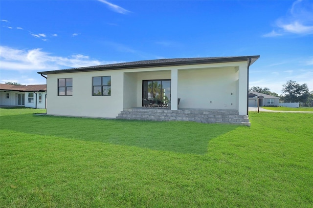 back of house with stucco siding and a lawn
