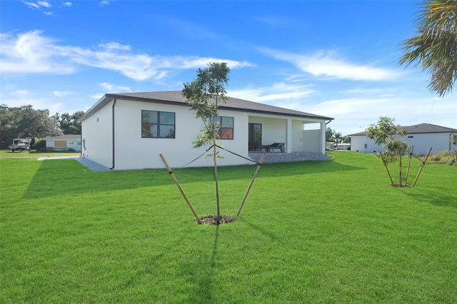 rear view of property featuring a yard and stucco siding