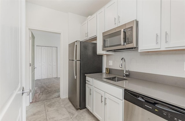 kitchen featuring white cabinetry, stainless steel appliances, decorative backsplash, and a sink