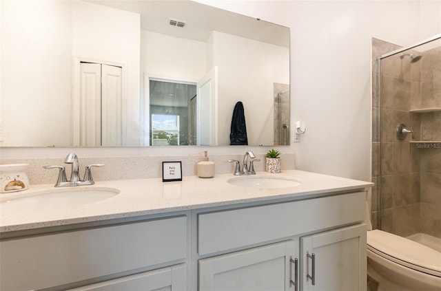 bathroom with toilet, a stall shower, double vanity, and a sink