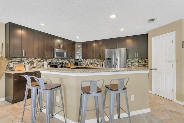 kitchen featuring a kitchen breakfast bar, visible vents, stainless steel appliances, and decorative backsplash
