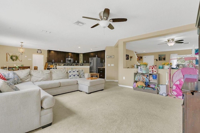 living room with visible vents, baseboards, light colored carpet, and ceiling fan with notable chandelier