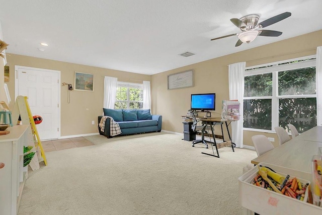 carpeted living room featuring baseboards, visible vents, and a ceiling fan