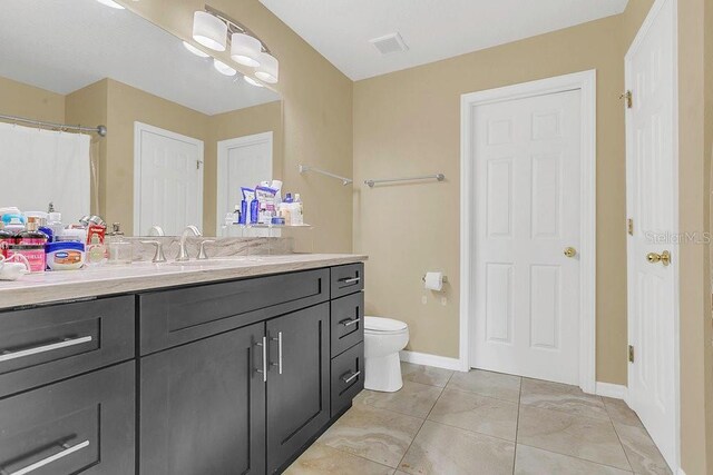 bathroom featuring visible vents, toilet, vanity, and baseboards