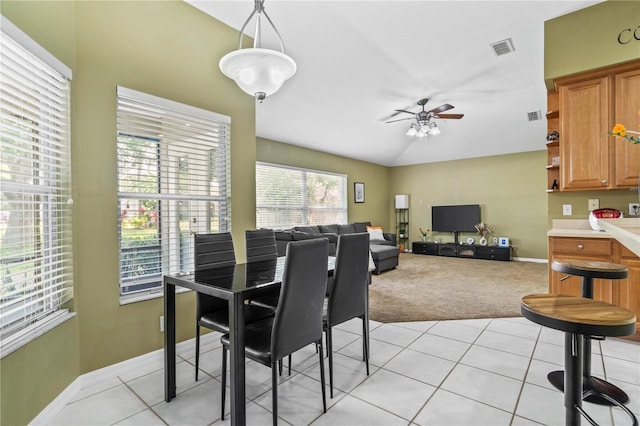 dining room with visible vents, light carpet, a ceiling fan, and light tile patterned floors