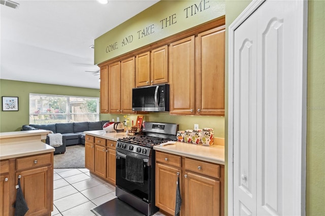 kitchen featuring light tile patterned floors, light countertops, gas stove, visible vents, and open floor plan
