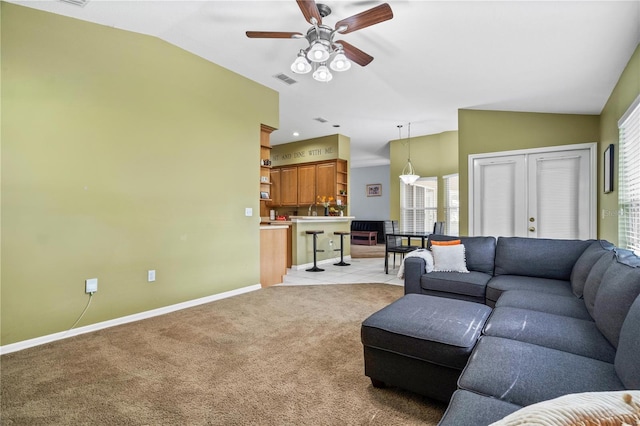 living area featuring a ceiling fan, vaulted ceiling, light carpet, and baseboards
