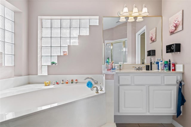 full bathroom featuring a chandelier, vanity, tile patterned floors, a stall shower, and a garden tub