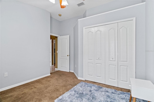 unfurnished bedroom with a closet, a ceiling fan, visible vents, carpet, and baseboards