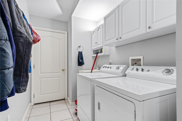 washroom with baseboards, light tile patterned floors, separate washer and dryer, and cabinet space