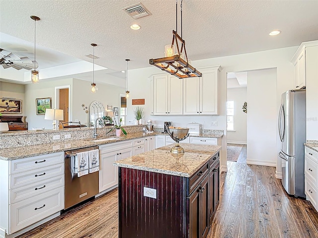 kitchen with appliances with stainless steel finishes, a sink, dark wood-style floors, visible vents, and a peninsula