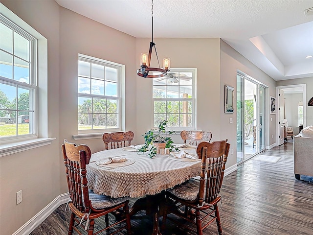 dining area with dark wood-style flooring, a wealth of natural light, a chandelier, and baseboards