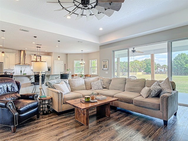 living room with a textured ceiling, ceiling fan, visible vents, recessed lighting, and dark wood-type flooring