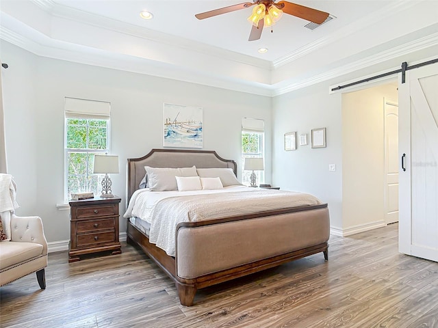 bedroom with visible vents, wood finished floors, and a raised ceiling